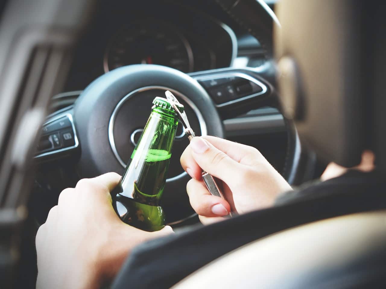 image of person opening beer at drivers wheel | Colorado accident lawyer