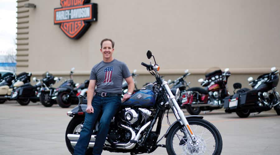 Scott O'Sullivan on motorcycle in front of Harley-Davison store