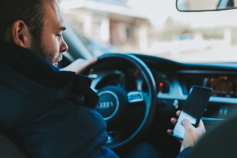 man using smartphone in car for dangerous denver roads